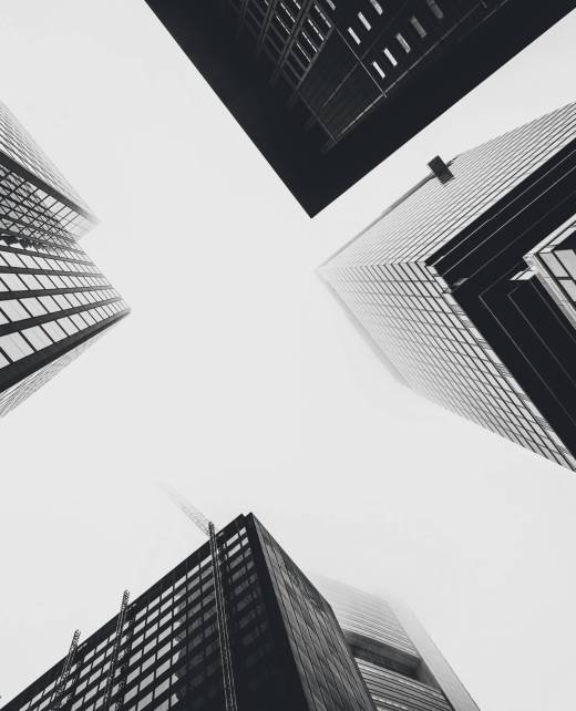 A low angle shot of modern glass city buildings on the background of the white sky